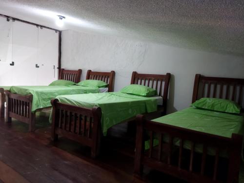 three beds in a room with green covers on them at Casa Prudente in Olinda