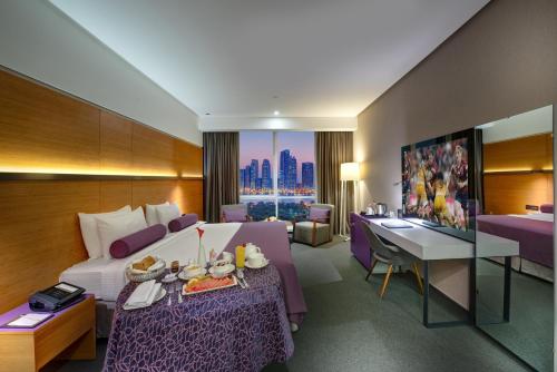a hotel room with a bed and a table with food on it at The Act Hotel Sharjah in Sharjah