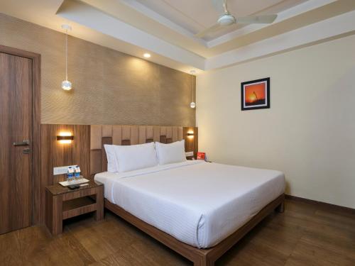 a bedroom with a large white bed and a table at Pride Biznotel Sasan Gir in Sasan Gir