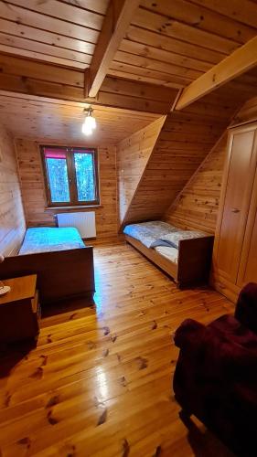 a room with two beds in a log cabin at Klimatyczny drewniany dom z kominkiem nad jeziorem Mielno w 2h z Warszawy i Gdanska in Olsztynek