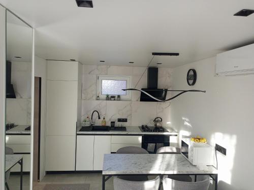 a white kitchen with a table and a sink at New and comfortable apartments in Uzhhorod