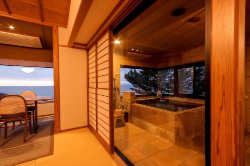 a bathroom with a tub and a dining room with a table at 海のほてる　いさば in Numazu