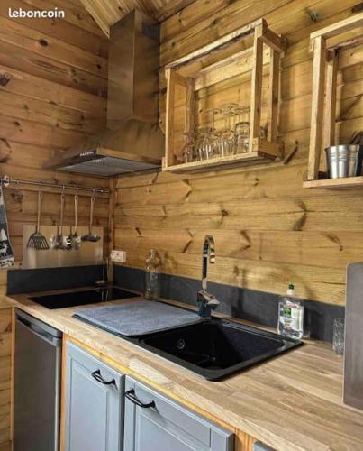 - une cuisine avec un évier et un mur en bois dans l'établissement Chalet Authentique - Insolite - Sauna & Télécabine - Ménage, serviettes, lit fait inclus, à Rochesson