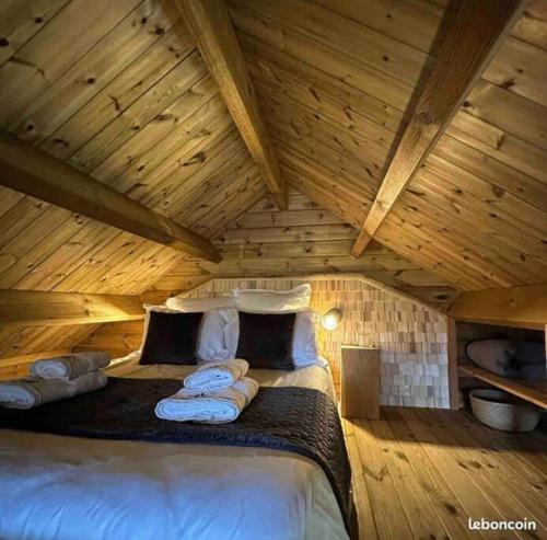 - une chambre avec un lit dans un grenier en bois dans l'établissement Chalet Authentique - Insolite - Sauna & Télécabine - Ménage, serviettes, lit fait inclus, à Rochesson