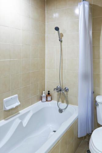 a bathroom with a tub and a toilet and a shower at Ravipha Residences in Bangkok