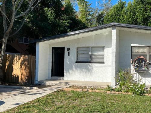 a small white building with a black door at Busch Gardens Bliss Retreat 1 Bedroom in Tampa