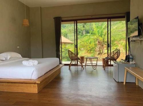 1 dormitorio con 1 cama, mesa y sillas en The Liveliwoods, en Khao Sok