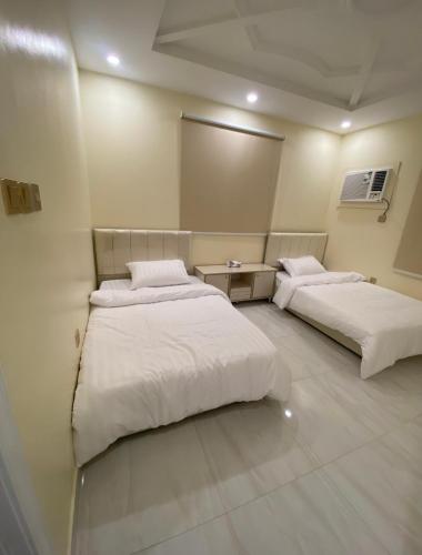 twee bedden in een kamer met witte lakens bij الضيافه in Jeddah