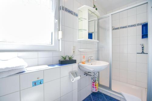 a white bathroom with a sink and a mirror at Ferienhaus Daheim in Borkum