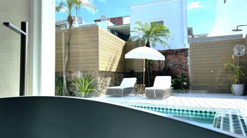 a swimming pool with two chairs and an umbrella at 拾嶼SheWill in Hengchun