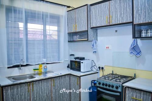 a small kitchen with a stove and a microwave at Mupa's Luxury Condo II in Nyahururu