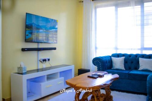 Sala de estar con sofá azul y mesa de centro en Mupa's Luxury Condo II, en Nyahururu