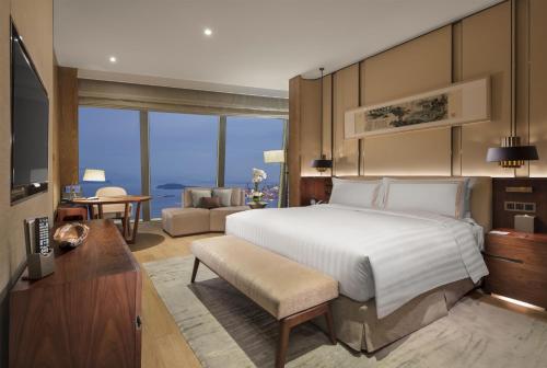 a bedroom with a large bed and a living room at Conrad Xiamen in Xiamen