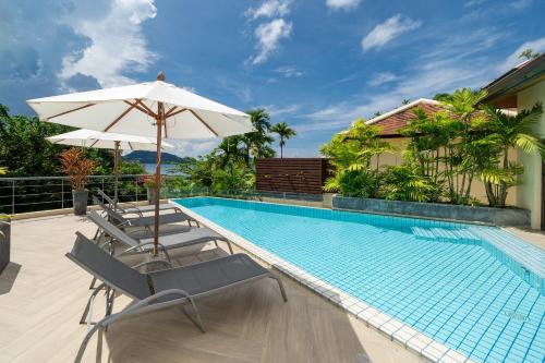 a swimming pool with two chairs and an umbrella at IndoChine Resort and Villas in Patong Beach