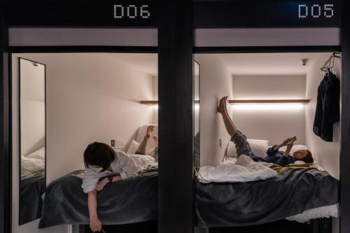 a group of people laying on beds in a room at The Millennials Kyoto in Kyoto