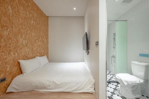 a bedroom with a white bed and a bathroom at Light Hostel Hualien in Hualien City