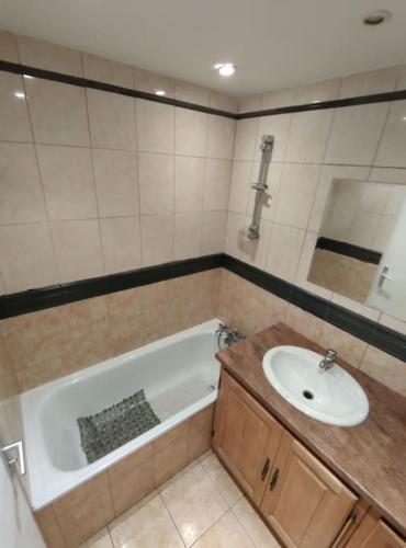 une salle de bain avec une baignoire et un lavabo dans l'établissement Duplex Cosy, à Gonesse