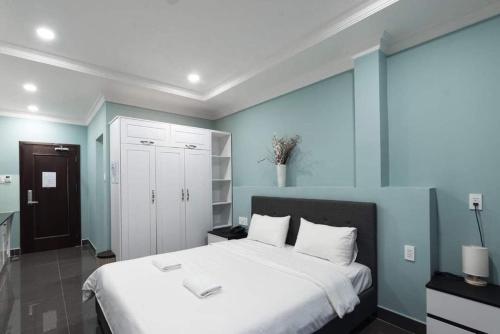 una camera da letto con un grande letto bianco e pareti blu di NEW MILANO HOTEL & APARTMENT ad Ho Chi Minh