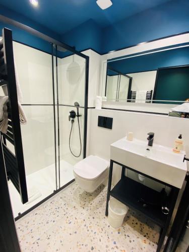 a bathroom with a shower and a toilet and a sink at Grand Hôtel Clichy Paris in Clichy