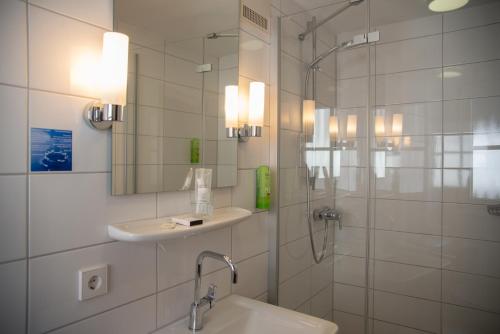 a bathroom with a shower and a sink and a mirror at Hotel Restaurant Schwarzer Adler in Bad Saulgau