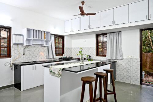 una cucina bianca con lavandino e 2 sgabelli da bar di YOGESH VILLA a Goa Velha