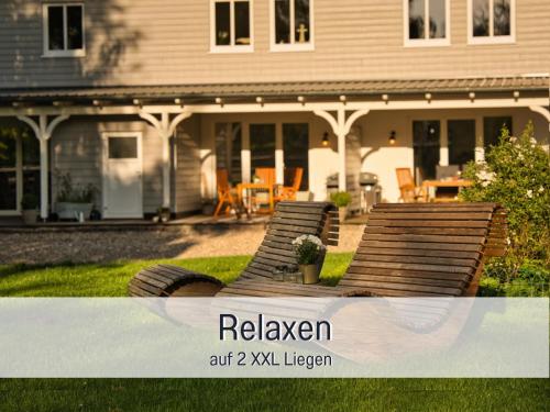 a house with two wooden benches in the yard at RamosHansenHof Fewo Hofglück 4Pers mit Hund in Steinberg