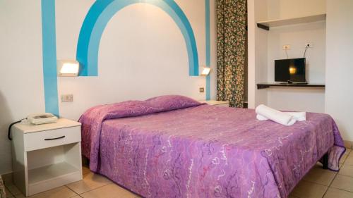 Villaggio Welcome Riviera d'Abruzzo في تورتوريتو ليدو: غرفة نوم مع سرير مع لحاف أرجواني