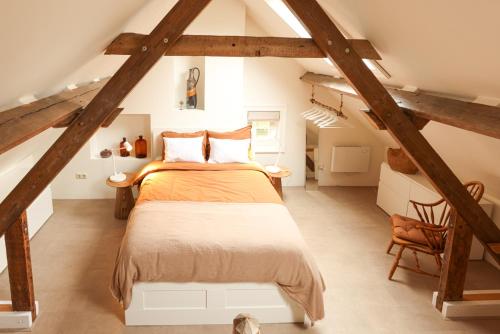 ein Schlafzimmer mit einem großen Bett im Dachgeschoss in der Unterkunft De Torteltuin in Nispen