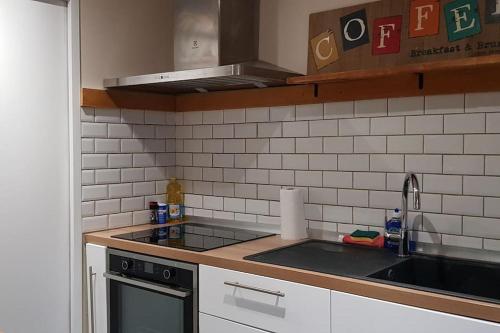 une cuisine avec un évier et une cuisinière dans l'établissement La Petite Maison des Pénitents., à Limoges