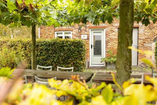 a wooden bench in front of a brick building with a door at De Torteltuin in Nispen