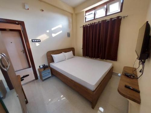 a bedroom with a bed and a window and a television at Hotel Hari Gayatri Regent in Guwahati