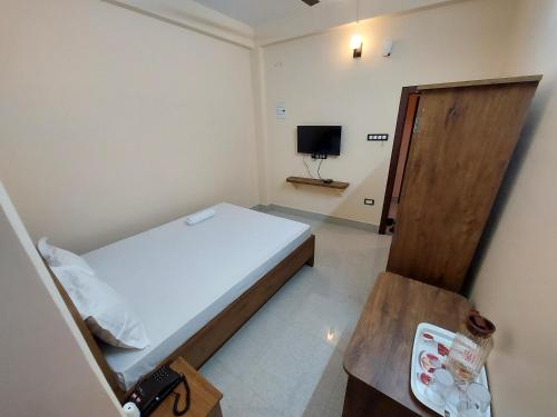 a small bedroom with a bed and a television at Hotel Hari Gayatri Regent in Guwahati