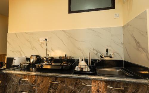 a kitchen counter with a sink and a stove at Himalayan Suite in Dharamshala