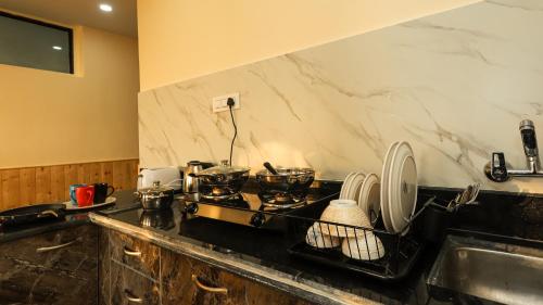 a kitchen counter with a stove and a sink at Himalayan Suite in Dharamshala