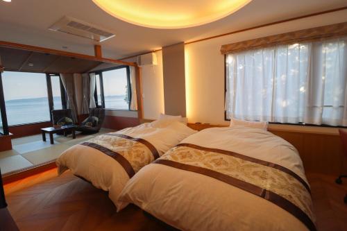 two beds in a room with a large window at La se ri Resort and Stay in Himi