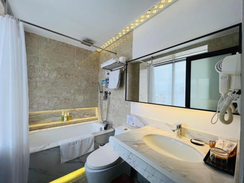 a bathroom with a sink and a mirror and a tub at Azumaya Hotel Hai Phong in Hai Phong