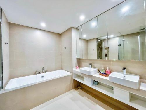 a bathroom with two sinks and a tub and a mirror at The Song Vung Tau By Abogo in Vung Tau