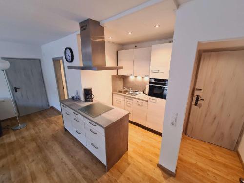 a kitchen with white cabinets and a wooden floor at Ferienwohnungen Golla-lang in Oberharmersbach
