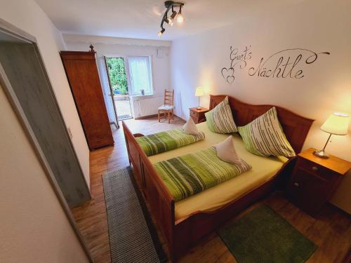 1 dormitorio con cama de madera y almohadas verdes en Ferienwohnungen Golla-lang, en Oberharmersbach