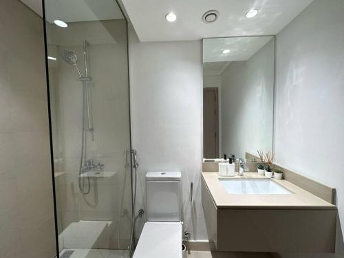 y baño con ducha, aseo y lavamanos. en Comfy is just a holiday home! 105WB2, en Abu Dabi