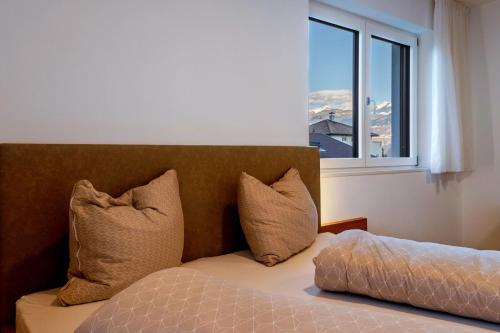 a bedroom with a bed with pillows and a window at Ferienwohnungen Karin - Cabernet in Termeno