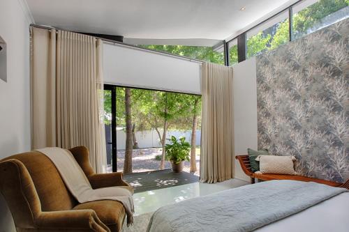 a bedroom with a bed and a chair and a window at The Risa House in Muldersdrift