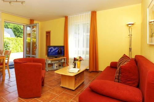 salon z czerwonymi kanapami i telewizorem w obiekcie Haus Clara Wohnung 1 w Koserowie