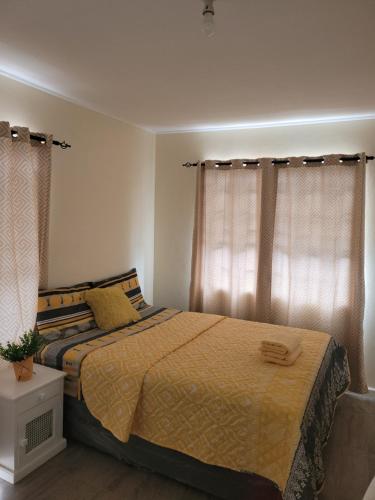 a bedroom with a bed with a yellow comforter and curtains at Kensington Oval- 2 bed 1 Bath in Bridgetown