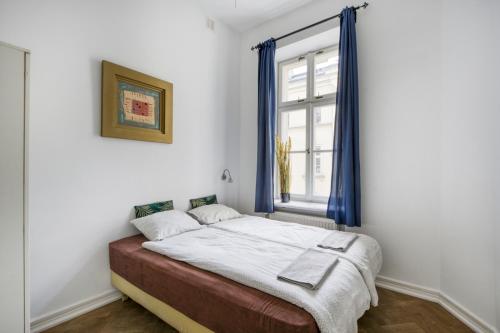 a bedroom with a bed with blue curtains and a window at Śliska Residence in Warsaw