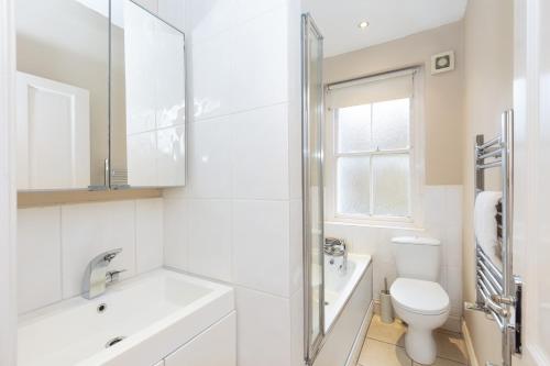 Baño blanco con lavabo y aseo en Beautiful 2BR Flat, Peaceful Dulwich, South London en Londres