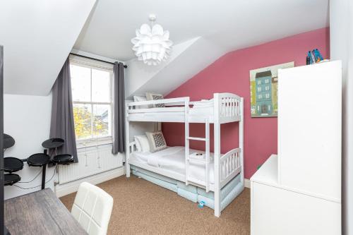 a bedroom with a white bunk bed and a pink wall at Beautiful 2BR Flat, Peaceful Dulwich, South London in London