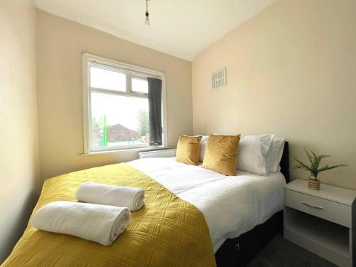 a bedroom with a large bed with yellow sheets and a window at (S12) Bright 3 Bed Home With Free Parking Leeds in Killingbeck