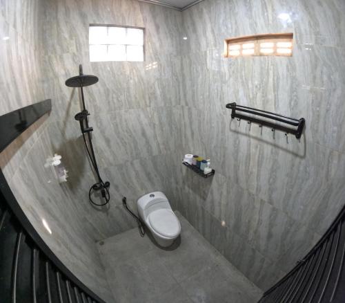 a bathroom with a toilet in a concrete wall at Omah Nogotirto Homestay Jogja in Ngingas