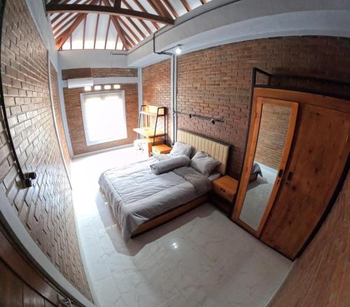1 dormitorio con 1 cama en una pared de ladrillo en Omah Nogotirto Homestay Jogja, en Ngingas